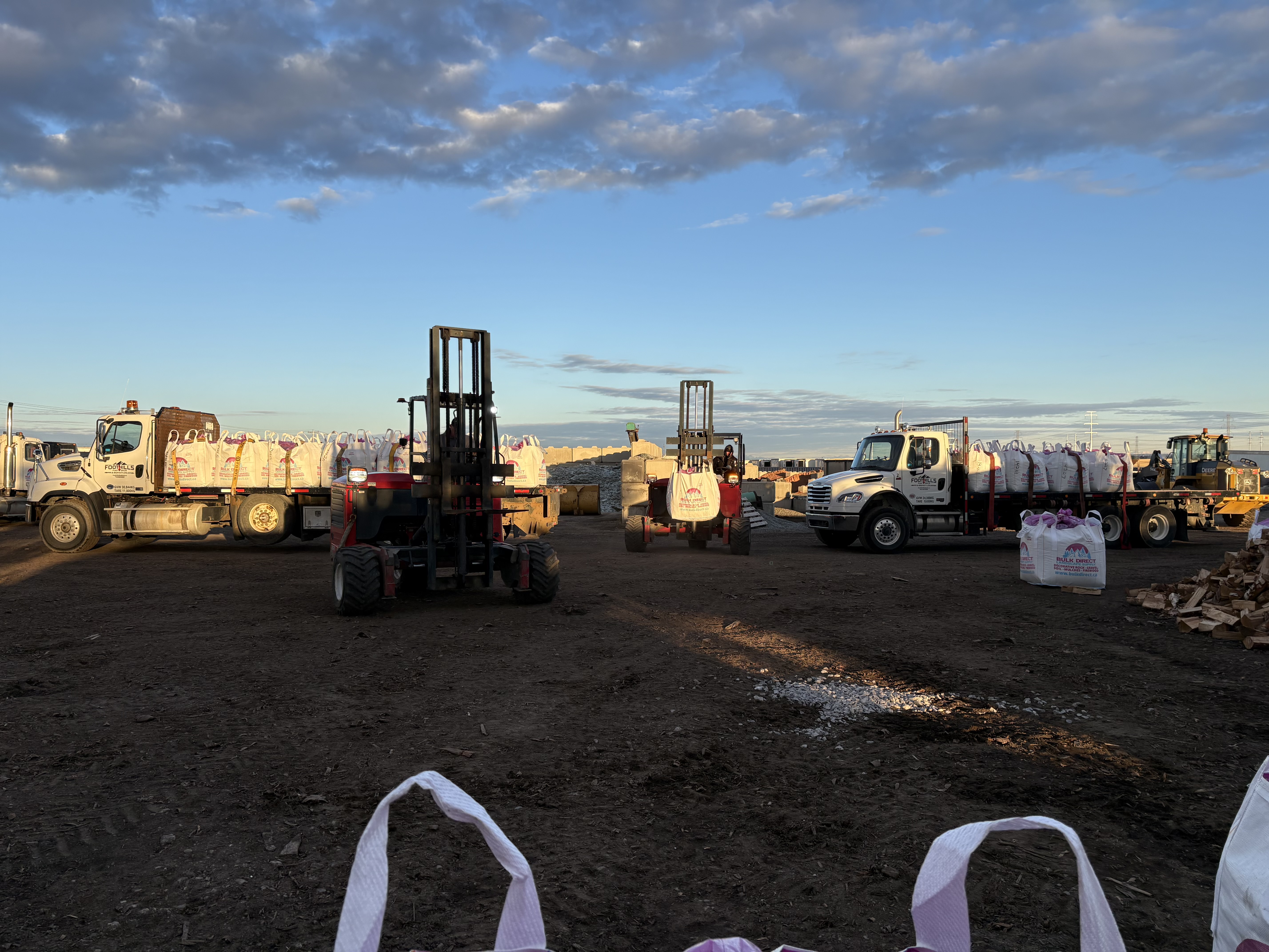 Foothills Flat Deck trucks and Moffett forklift on the job site — Calgary, AB